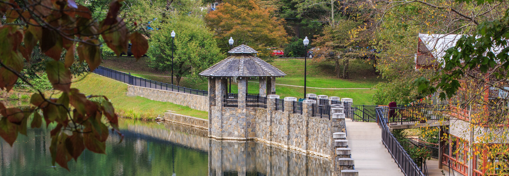 A stone walkway and gazebo overlook Lake Susan at the Montreat Conference Center in North Carolina, surrounded by lush trees.