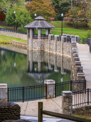 A stone walkway and gazebo overlook Lake Susan at the Montreat Conference Center in North Carolina, surrounded by lush trees.