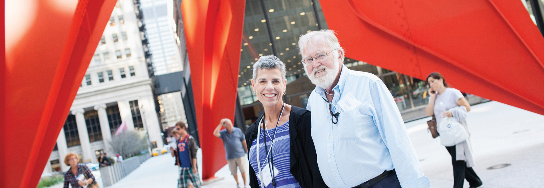 A smiling couple stands in front of Alexander Calder's large red "Flamingo" sculpture in downtown Chicago, Illinois.