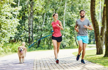 Športen par s psom teče na poti v parku.