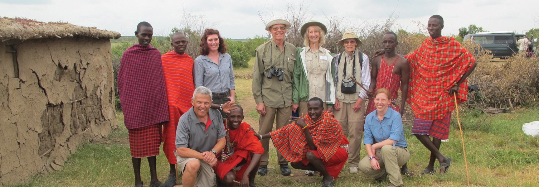 A group of travelers and Maasai men pose together for a photo in a village in Tanzania.