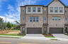 front of 3-story townhome with dark brick and light siding 