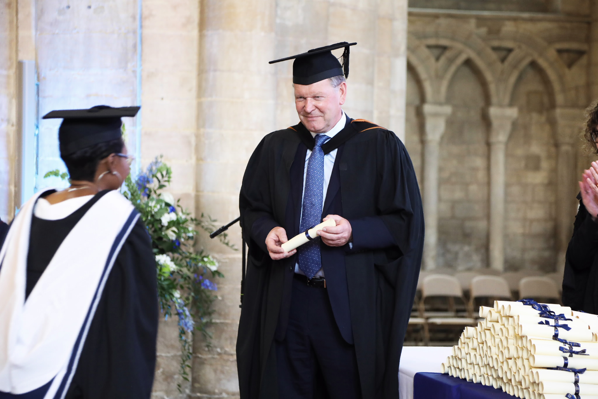 A male official presents a rolled diploma to a graduate