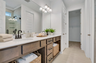 primary bathroom with double sink vanity, wood cabinets, tile flooring, and a glass shower