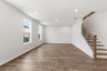 great room with wood flooring, large windows, and a view of the staircase