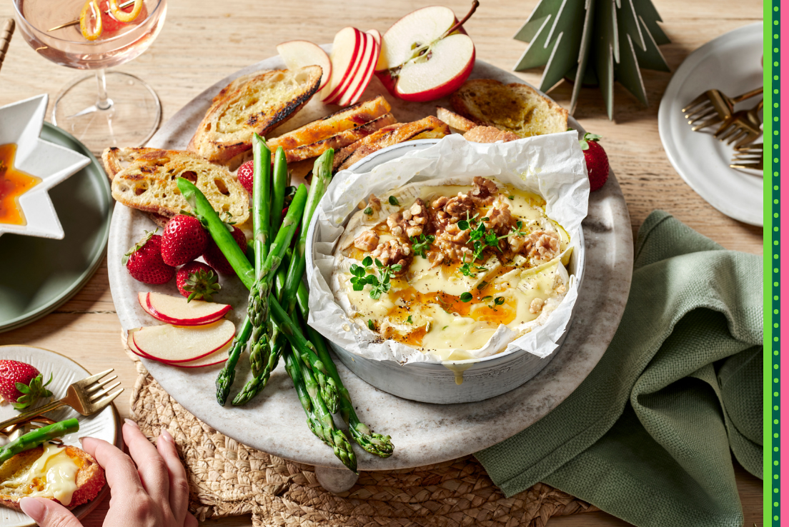 Baked brie topped with sweet and savoury walnuts and honey and served on a platter with asparagus, apples, strawberries and toasted sourdough