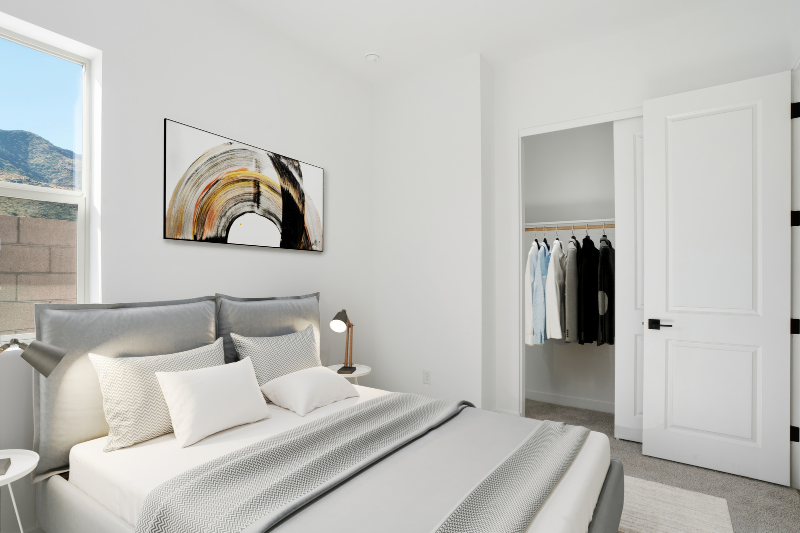 bedroom with a large bed, grey bed covers, and nightstands with lamps