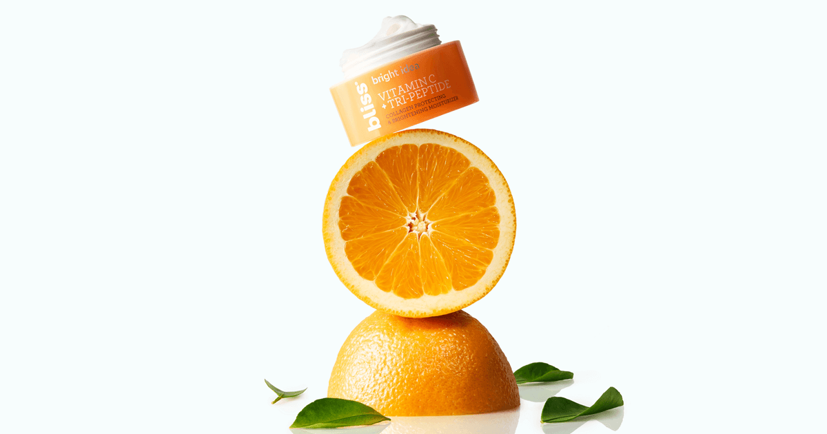 Image of an orange and half of an orange stacked on top of each other with a skin cream container at the top. 