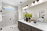 bathroom with two sinks, brown cabinets and black hardware and tile with shower