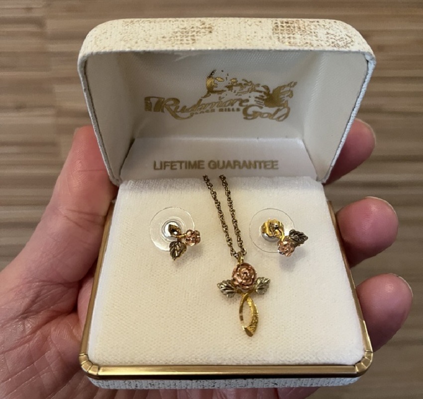 A gold necklace and earrings in a white jewelry box