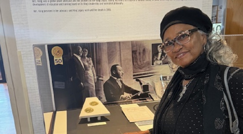 Elaine smiles in front of an exhibit on Dr. Martin Luther King, Jr. and Coretta Scott King