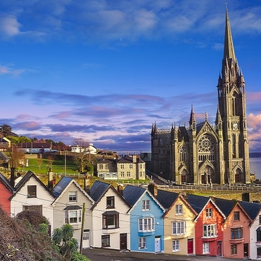 Colorful houses stand in a line in front of a church