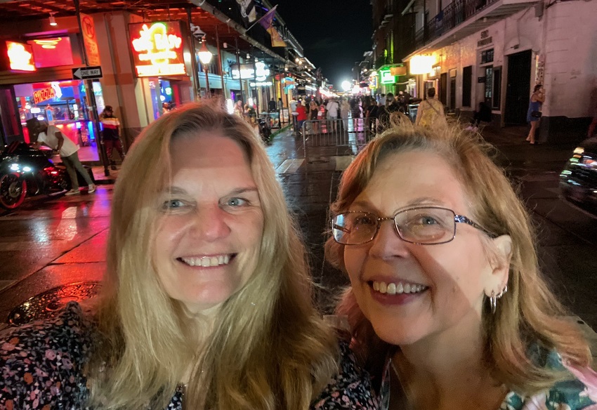 Laura and Dawn smile in front of New Orleans streets lit up at night