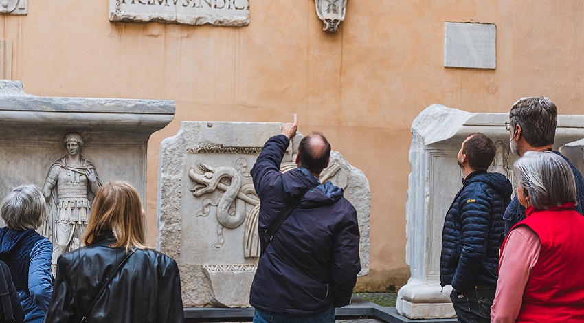 An instructor points at artifacts, while participants look on