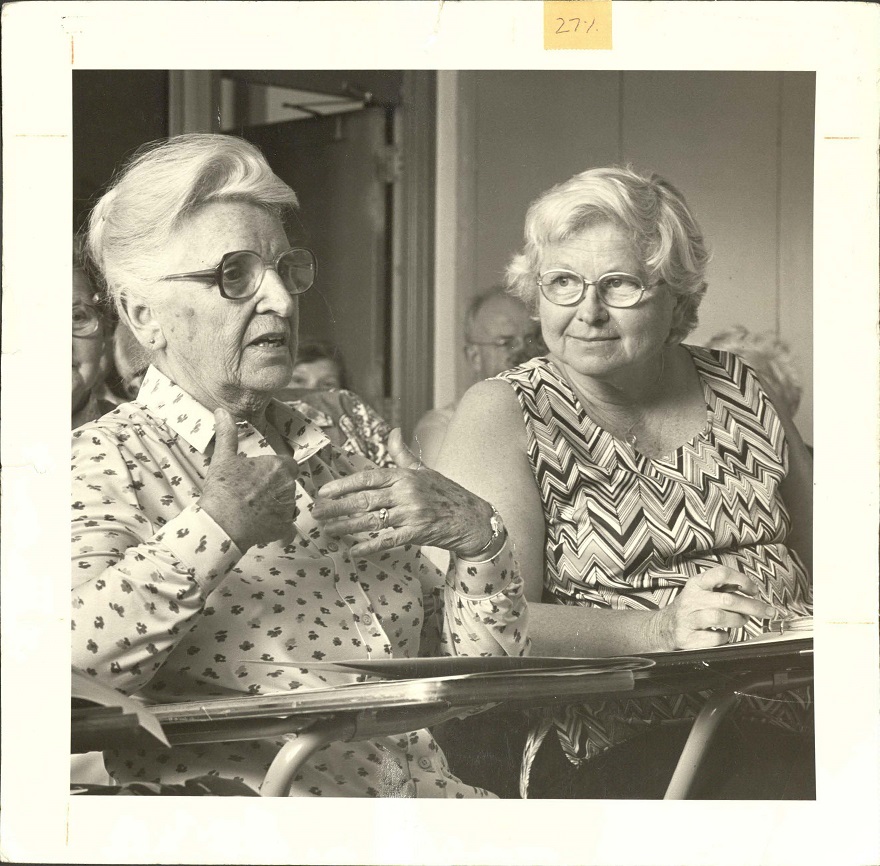 An older photo of two women sitting in a classroom engaged in discussion