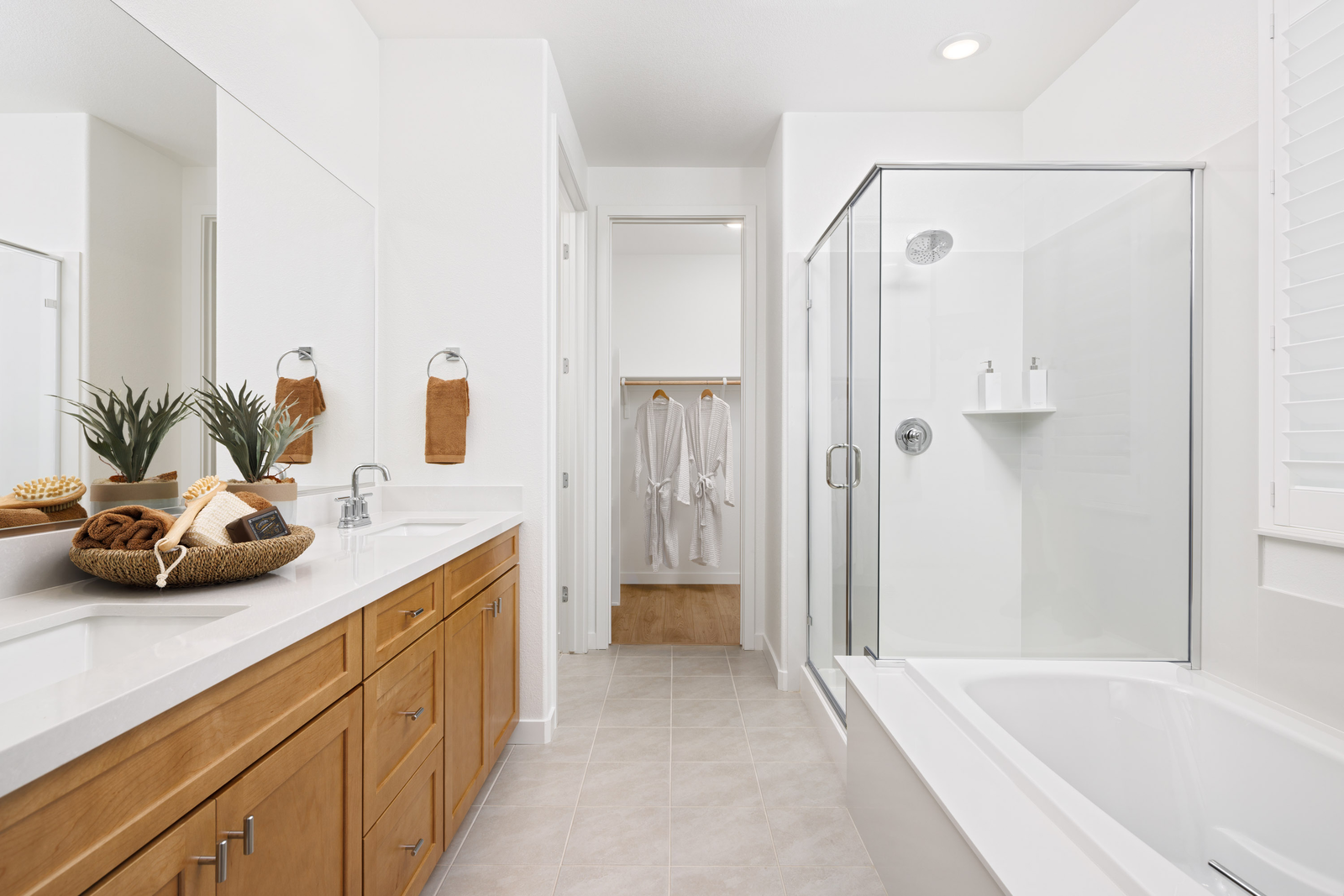 bathroom with light wood cabinets, white counters, tan tile floors, walk-in shower, and separate tub