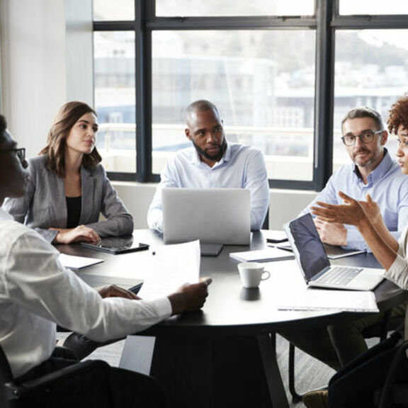 Businesspeople having discussion around table with laptops