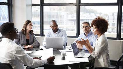 Businesspeople having discussion around table with laptops
