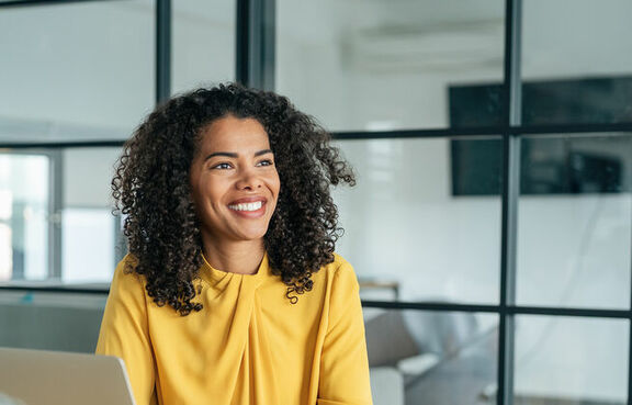 Business woman in a yellow blouse sitting at a conference table with laptop