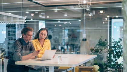Man and woman at a desk looking at a laptop