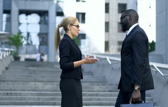 Professional woman and man talking outside in front of concrete stairs
