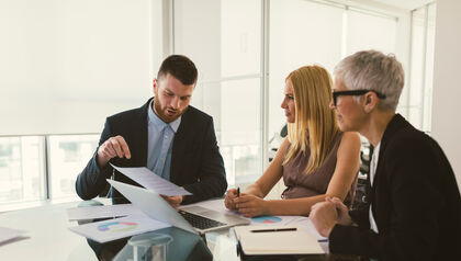 Man and two women at a table looking at papers