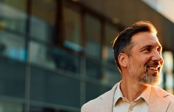 Businessman outside and smiling with smartphone