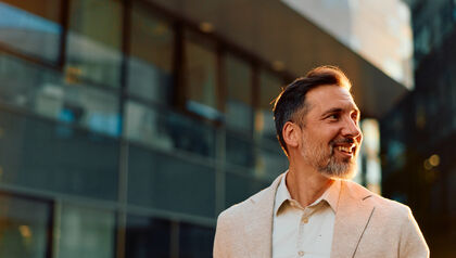 Businessman outside and smiling with smartphone