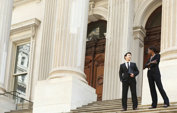 Two lawyers standing on the stairs of a courthouse