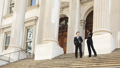 Two lawyers standing on the stairs of a courthouse