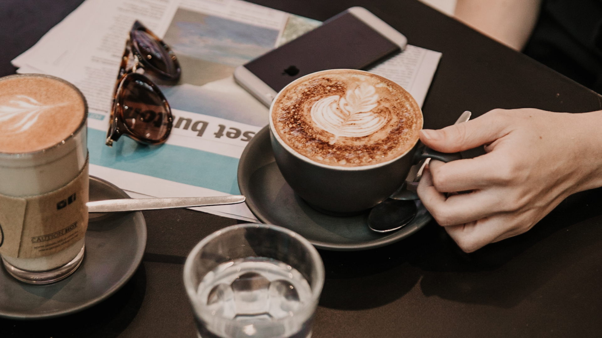 Coffees on a table with a phone and sunglasses