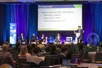 Photo of a person on stage at a podium discussing CAR T-cell therapy