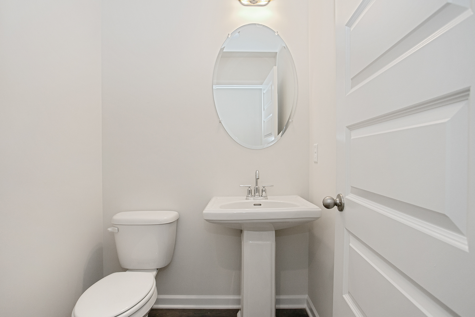 powder room with oval mirror and white finishes