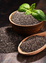 Bowl of chia seeds on wooden table.