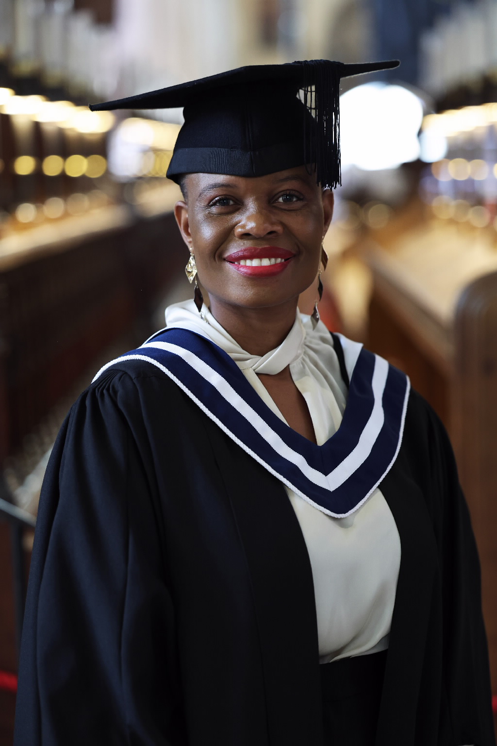 Close-up portrait of a smiling female graduate with red lipstick and bright top