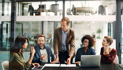 Group of coworkers in a meeting room looking at papers 