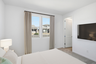 bedroom with a large white bed, a mounted tv, and a nightstand lamp