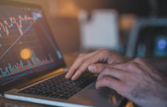 Man using a laptop to check a graph of cryptocurrency trends