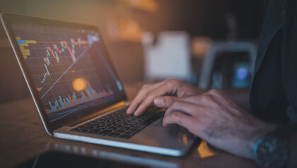 Man using a laptop to check a graph of cryptocurrency trends