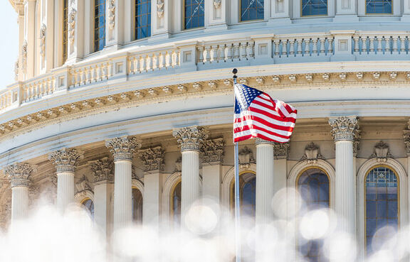 Close up of the Capitol Hill building with an American flag waving in front of it