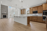 kitchen with wood cabinets, white countertops, large island with accent lighting, built in microwave and oven, and stainless steel appliances