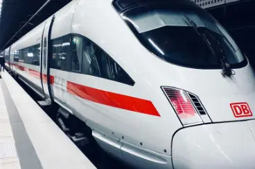 A close-up view of the front of a modern, white and red high-speed train (likely a German ICE train) stopped at a dark station platform.