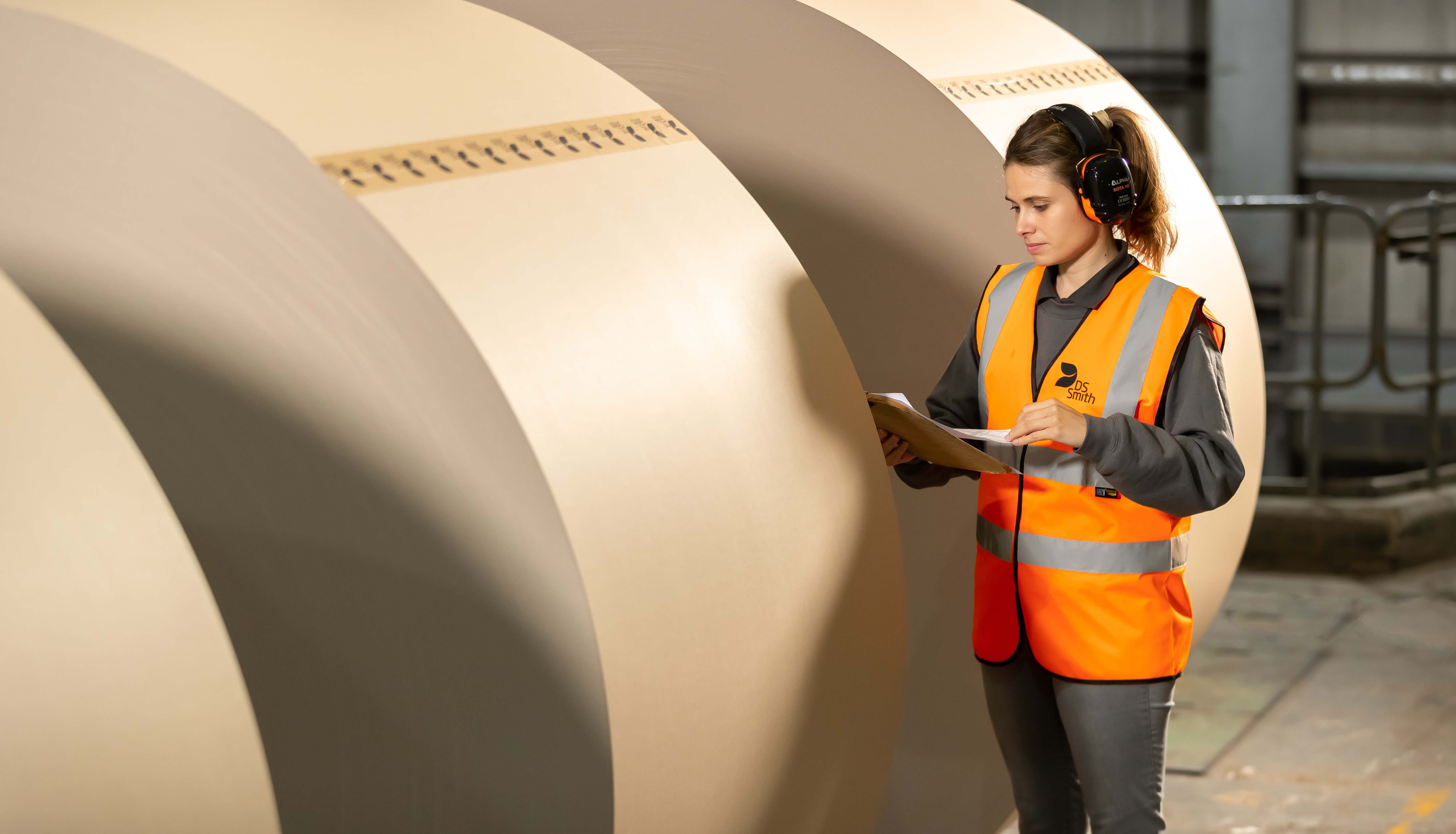 a person standing next to a reel of paper
