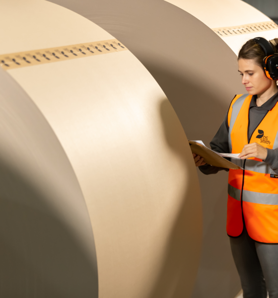 a person standing next to a reel of paper