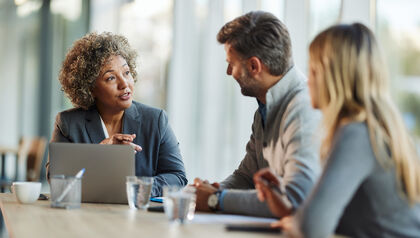 Female insurance agent talking to a couple at her desk