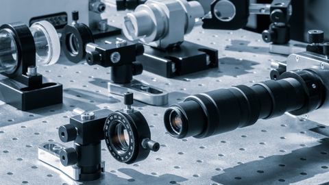 Optical equipment including telescope and lenses are displayed on a table in a laboratory
