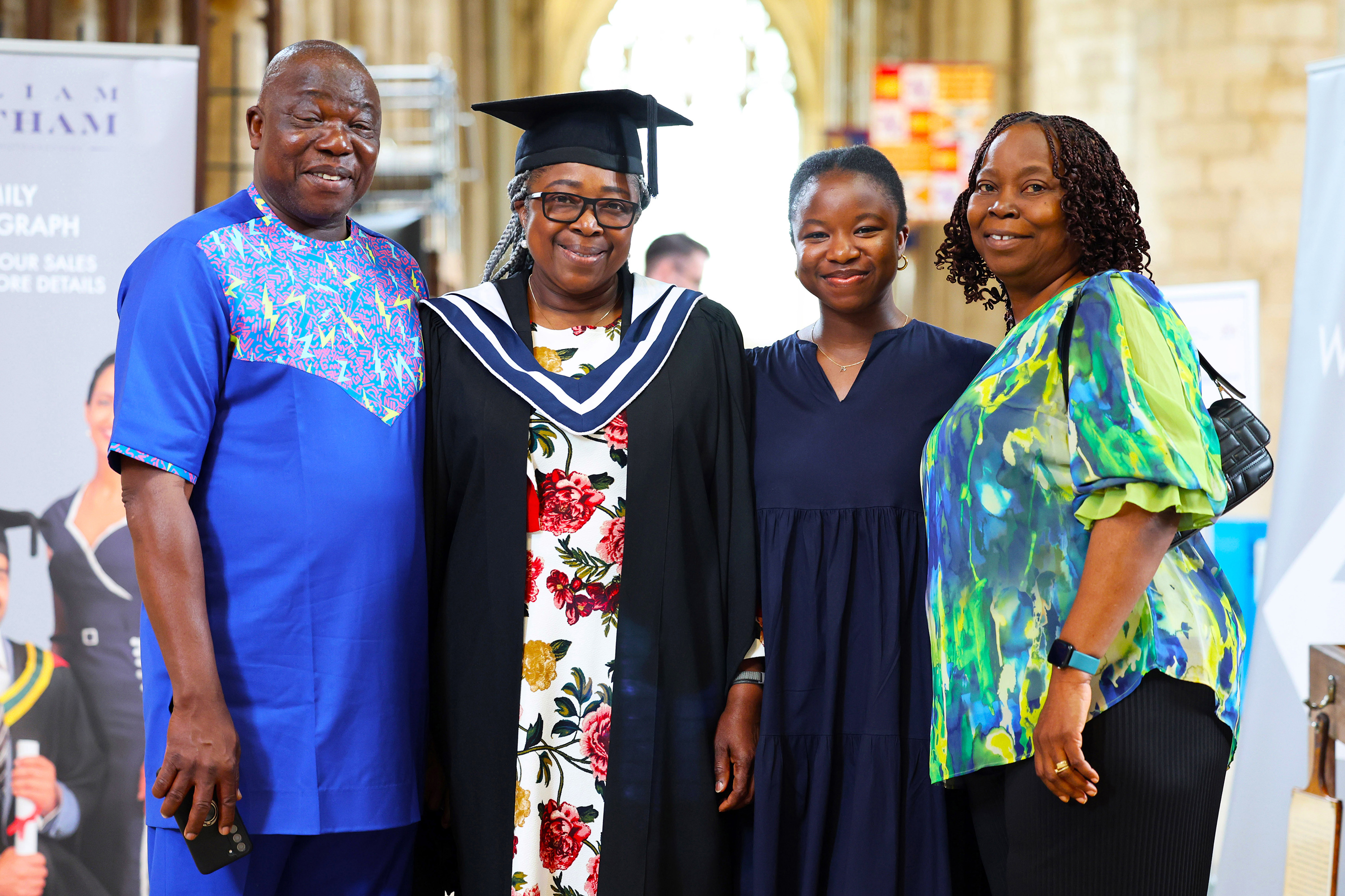Graduate in academic dress posing with three family members