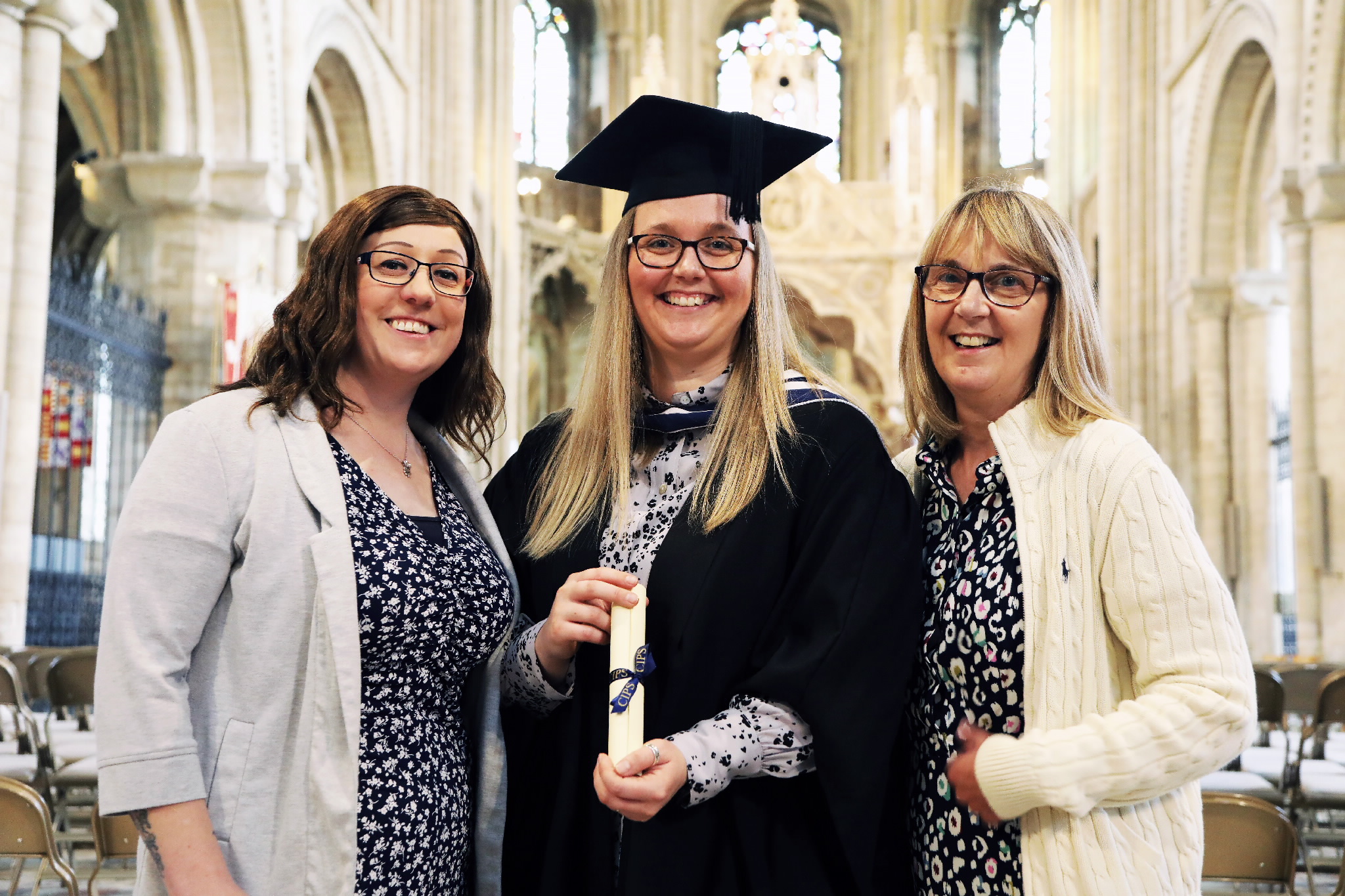 Graduate with her two guests smiling inside the cathedral