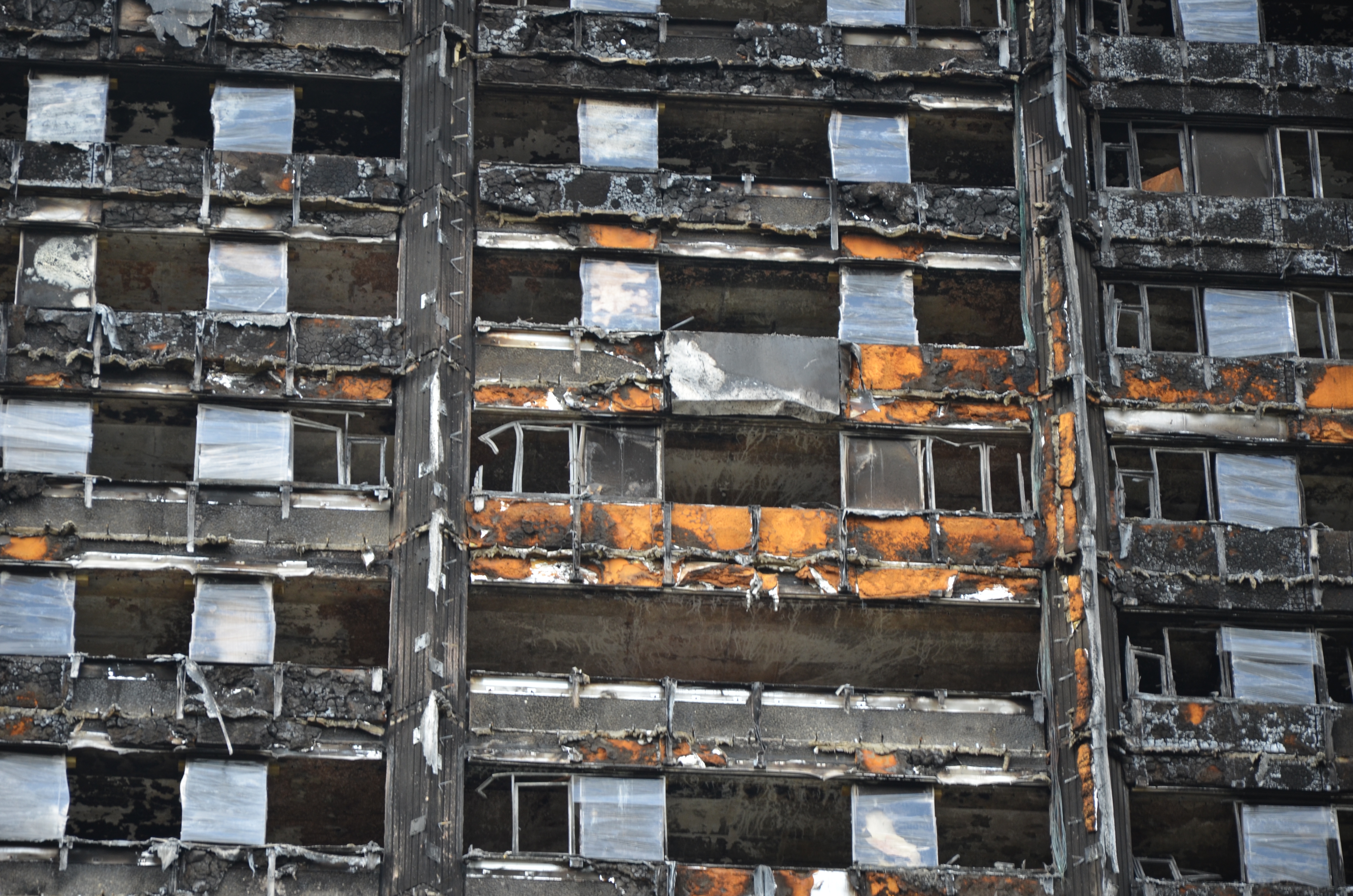 Close-up of grenfell tower, taken after the fire destroyed it. Building looks destroyed, windows are no longer in their frames and outer material is severely damaged