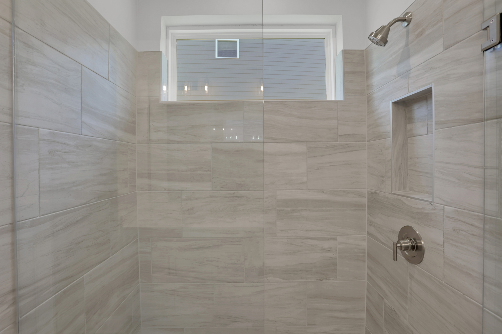 primary bathroom with large walk-in shower with light tile 